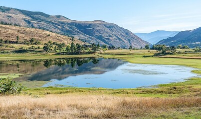 Fototapeta premium Serene mountain lake reflecting hills and trees in a tranquil valley landscape.