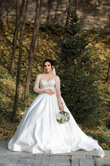 The bride has dark hair tied up in an updo and is holding a bouquet of white flowers in her hands. A wooden fence and sidewalk are visible in the background