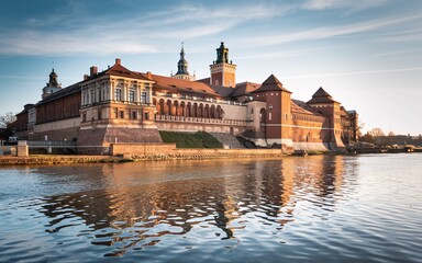 Obraz premium Krakow's Wawel Castle, Poland Majestic riverside castle reflecting in calm water at sunrise.