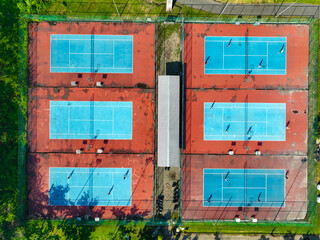 Aerial View of Six Tennis Courts in a Park, Players Engaging in Matches, Sunny Day