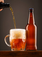 A bottle of beer and a glass of beer on a dark background.