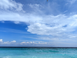 Stunning turquoise ocean under a vibrant blue sky with fluffy white clouds. Peaceful beach scene. Perfect for travel, nature, or summer themes