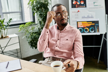 Focused young man enjoying coffee while working remotely in a modern workspace