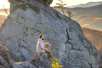 Bearded climber sitting on a rock, admiring the highland landscape surrounded by mountain walls