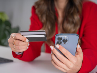 Close up cropped image of female hands holding credit card and smartphone, young caucasian business...