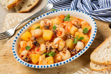 Close up of Cuttlefish stew with potatoes. Bread. Spanish meal.