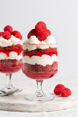 Close up of Red Velvet Trifle, layers of red velvet cake, mascarpone cheese cream, berry jelly, fresh  raspberries. Festive Homemade dessert for Christmas or Valentines Day. Vertical image.
