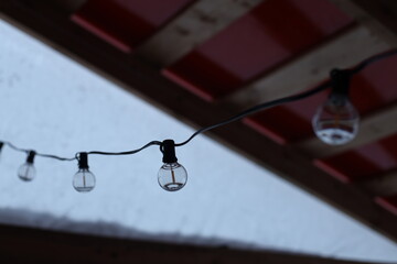 String of light bulbs hanging from a roof, ideal for party or event decorations.