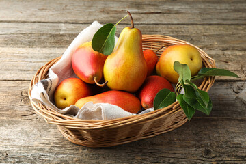Ripe juicy pears in wicker basket on wooden table