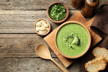 Delicious broccoli cream soup served on wooden table, flat lay. Space for text