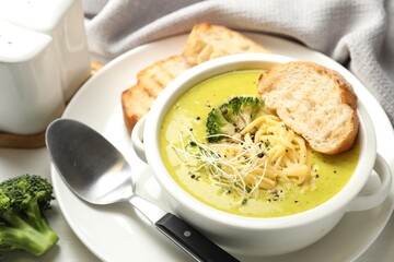Delicious broccoli cream soup served on table, closeup