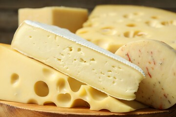 Different types of cheese on wooden board, closeup