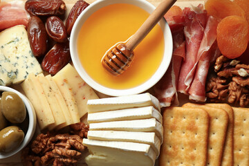 Different types of delicious cheese and other snacks as background, top view