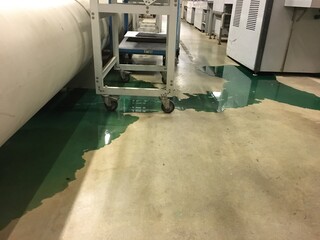 Industrial Facility with Green Liquid Spill on Concrete Floor