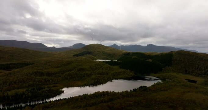 Wide drone view over lake of wind turbines in alpine landscape of Sortland