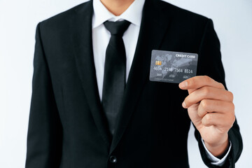 Portrait of businessman holding a credit card showing front view to the camera in close up view. Online shopping business and cashless payment concept. uds