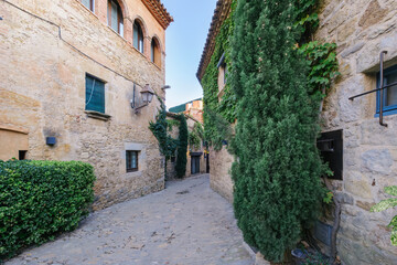 Naklejka premium Rustic Stone House Covered with Green Ivy. Traditional Mediterranean Architecture in a Picturesque Village. Peratallada is a town on the Costa Brava, in northern Spain, Catalonia.