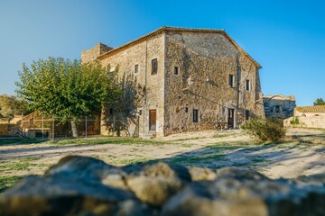 Fototapeta premium Ancient Stone Farmhouse in Medieval Village Setting. Historic Rural Architecture in Peratallada with Weathered Walls and Defense Tower (Historical Farmhouse in Peratallada) Catalonia, Spain