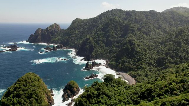 4K drone video of Orong Bukal Viewpoint. The blue ocean crashes against cliffs and lush green landscapes amongst the mountains in Lombok, Indonesia