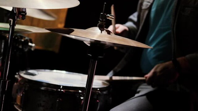 A drummer plays a snare drum and hi-hat cymbals during a live jam session, captured in low lighting for an intimate and artistic feel