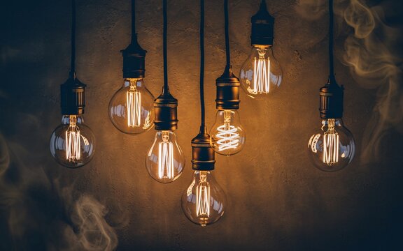 illuminated light bulb, Glowing vintage Edison light bulbs hanging against a smoky dark background.