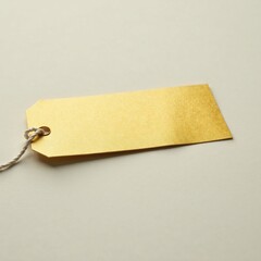 An isolated golden label lies flat against a neutral-colored surface with string absent, minimalist, surface, empty space