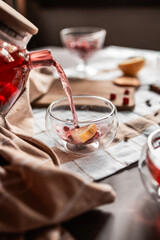 drops of red tea, woman pouring tea into a glass cup, hibiscus, tea with red berries, vitamin drink, winter tea for colds, lemon, red currant, black currant, raspberry, honey, cinnamon, anise