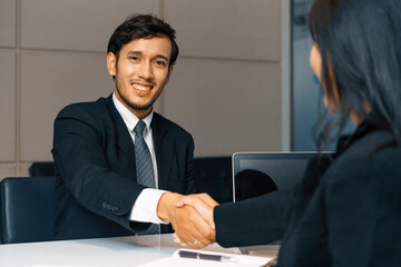 Business people agreement concept. Businessman and Asian businesswoman do handshake in the office. uds