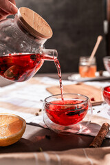drops of red tea, woman pouring tea into a glass cup, hibiscus, tea with red berries, vitamin drink, winter tea for colds, lemon, red currant, black currant, raspberry, honey, cinnamon, anise