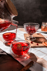drops of red tea, woman pouring tea into a glass cup, hibiscus, tea with red berries, vitamin drink, winter tea for colds, lemon, red currant, black currant, raspberry, honey, cinnamon, anise