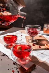 drops of red tea, woman pouring tea into a glass cup, hibiscus, tea with red berries, vitamin drink, winter tea for colds, lemon, red currant, black currant, raspberry, honey, cinnamon, anise