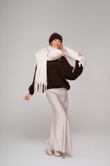 Trendy woman in stylish spring,autumn outfit smiling to the camera while posing on studio background.