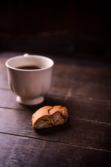 Cantuccini (Italian cookies) and a cup of coffee on dark wooden background. Close up..