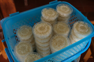 Close up of Khao Mak in plastic cup. Khao Mak is a type of Thai dessert, It is made from steaming glutinous rice and then fermenting it with mold and yeast in the form of flour in a blue basket.