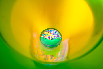A dynamic view inside a bright green slide leading to a colorful ball pit.