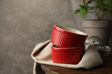 Red ceramic casseroles, sieve and whisk on wooden table, space for text