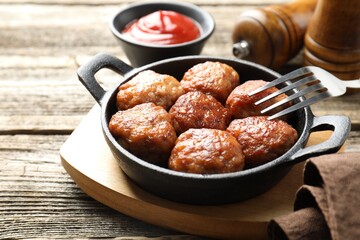 Tasty meatballs in baking dish served on wooden table, closeup