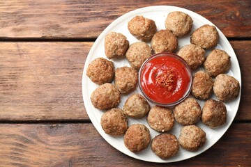 Delicious meatballs with ketchup and spices on wooden table, top view. Space for text