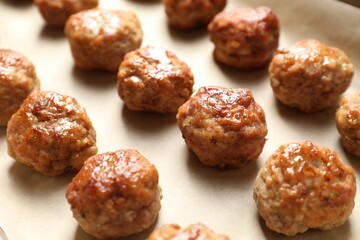 Many delicious meatballs on parchment, closeup view