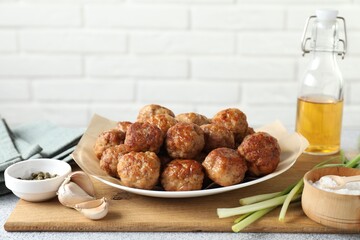 Many delicious meatballs, green onion, garlic, oil and spices on light textured table