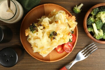 Tasty pasta casserole with cheese and broccoli served on wooden table, flat lay