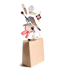 Different makeup products falling into paper shopping bag on white background. Decorative cosmetics