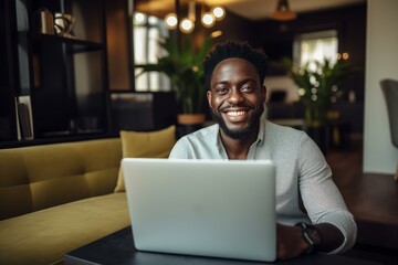 Happy black man using laptop, enjoying remote work in comfortable home office