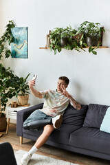 Young man with prosthetic leg joyfully taking a selfie in a cozy living room filled with plants