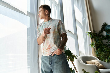A young man with a prosthetic leg stands by sunlight filled windows, contemplating life in style