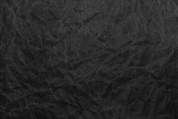 A sheet of wrinkled black color paper texture as background