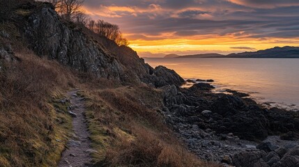 Coastal sunset path with rocky shore and dramatic sky.