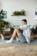 Young man with prosthetic leg stretching at home among plants and cozy decor