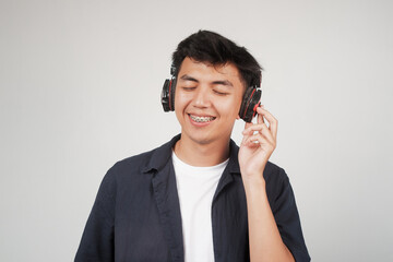 Close up a young Asian man enjoys listening music with headphones