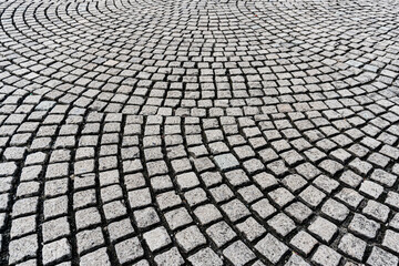 A circular pattern of gray cobblestones laid out in an arc, creating a textured, repeating design.